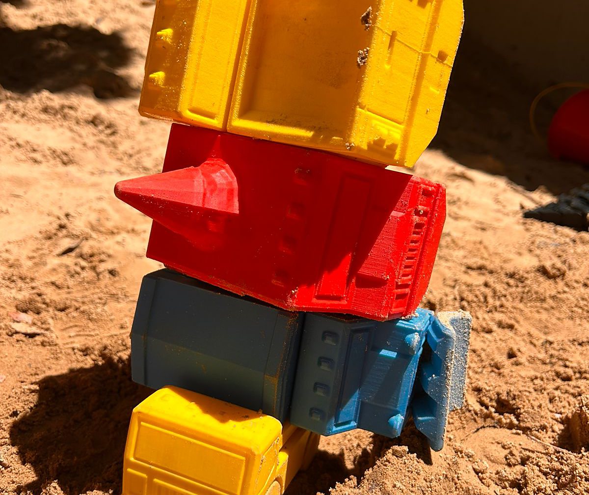3D-gedrukte speelgoedtrokke gestapel in die sandput